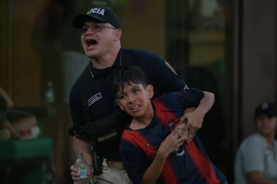 Policía ayuda a fan en medio de la pelea en las gradas del Olimpia vs Cerro Porteño / Foto: AFP