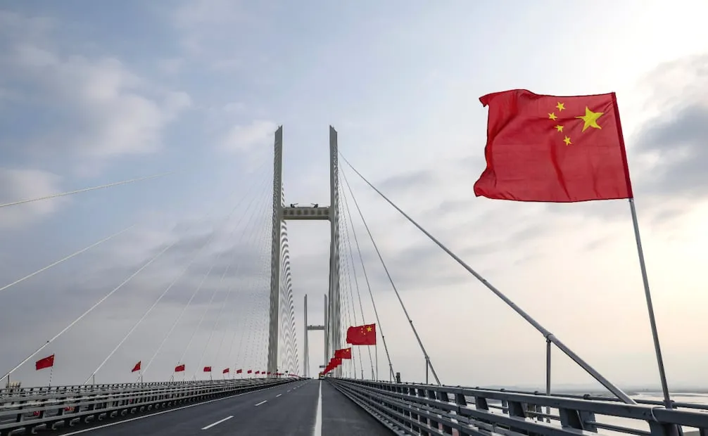 Banderas chinas ondean durante la ceremonia de apertura del puente que corre sobre el rio Yula. Foto: Pan Yulong/Xinhua via AP